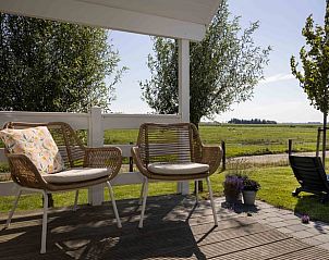 Zithoek op de veranda van Huisje in Greonterp met uitzicht op weilanden, Friesland.