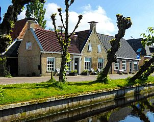 Rustige waterkant met boot bij vakantiehuis FR417 in Eastermar, Friesland.