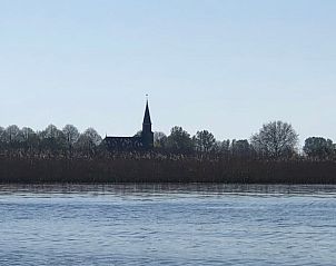 Uitzicht op een kerk vanaf het water dichtbij Vakantiehuis in Munnekeburen, Friesland.