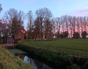 Vakantiehuis in Munnekeburen bij zonsondergang, met uitzicht op de natuur in Friesland.