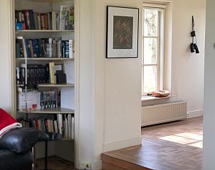 Boekenkast en zithoek in Vakantiehuis in Munnekeburen, ideaal voor ontspanning in Friesland.