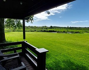 Veranda van Vakantiehuisje in Munnekeburen met uitzicht op weelderige velden in Friesland.