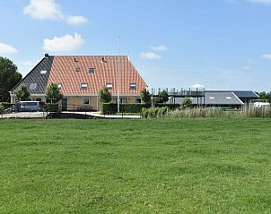 Uitzicht op het vakantiehuis Recreatieboerderij Slachtehiem in Lollum, Friesland, omgeven door groen.