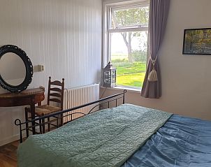 Slaapkamer met uitzicht op de tuin in Vakantiehuis in Lollum, Friesland.