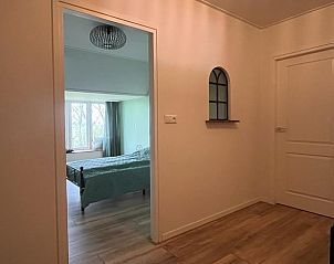 Slaapkamer met grote ramen in Vakantiehuis in Lollum, uitzicht op het groen.