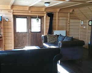 Knusse woonkamer in Vakantiehuisje in Drogeham, Friesland, met houten interieur en comfortabele banken.