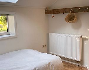 Knusse slaapkamer in Vakantiehuisje in Longa met natuurlijk licht en rustieke details.