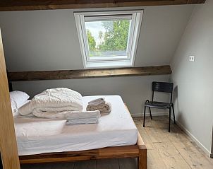 Slaapkamer met houten bed in Vakantiehuis in Surhuisterveen, knusse sfeer, Friesland.