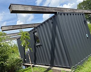 Zijaanzicht van het vakantiehuis in Surhuisterveen te midden van het groene Friese platteland.