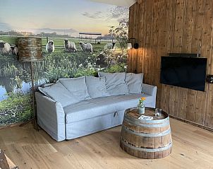 Gezellige zithoek in Huisje in Gonga met muurdecoratie van Friese schapen en houten meubels.