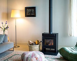 Gezellige woonkamer met houtkachel in Vakantiehuisje in Tzummarum, perfect voor ontspannen op het Friese platteland.
