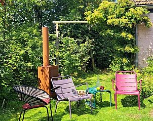 Buitenruimte met kleurrijke stoelen en groene omgeving bij Vakantiehuisje in Tzummarum, Friesland.