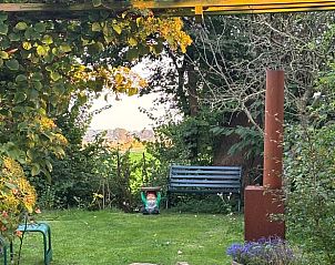 Tuinhoek met zitgelegenheid in Vakantiehuisje in Tzummarum, omgeven door groen in Friesland.