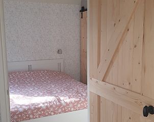 Sfeervolle slaapkamer met houten deur in Vakantiehuis in Wjelsryp, Friesland.