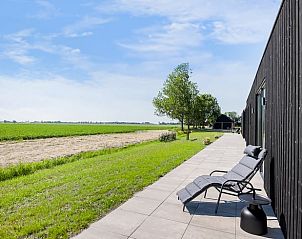 Terras met ligstoelen in Vakantiehuis in Slappeterp, Friesland met uitzicht op de natuur.