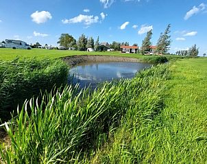 Vijver in de omgeving van Huisje in Swichum met groene velden, op het Friese platteland, Friesland.