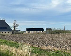 Uitzicht op Vakantiehuis in Sexbierum vanaf het Friese platteland met windmolens.
