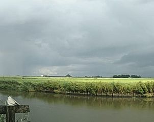Uitzicht op het Friese platteland vanaf Vakantiehuis in Achlum, Friesland, met weidse groene velden.