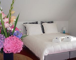 Luxe slaapkamer in Vakantiehuisje in Gytsjerk met frisse bloemen en comfortabel bed.
