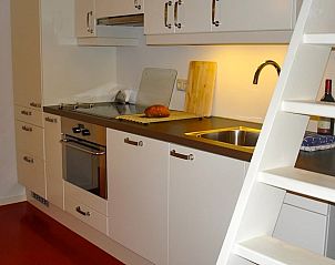 Moderne keuken in Vakantiehuisje in Gytsjerk met strakke witte kasten en trap.