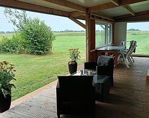 Geniet van het uitzicht vanaf de veranda van Vakantiehuis in De Wilgen, gelegen op het Friese platteland in Friesland.