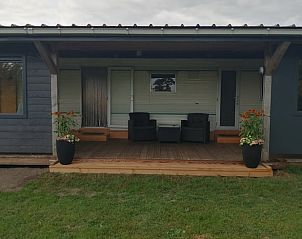 Veranda van Vakantiehuis in De Wilgen, gelegen op het Friese platteland in Friesland, met comfortabele stoelen en groene omgeving.
