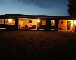 Verlichte avondzicht op Vakantiehuis in De Wilgen, gelegen op het Friese platteland in Friesland, met uitnodigende veranda.