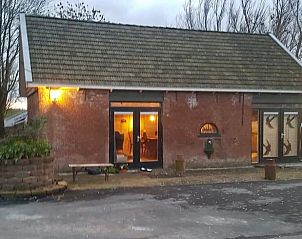 Buitenkant van het Vakantiehuis in Sint Annaparochie, Friesland, met traditionele bakstenen gevel en sfeervolle verlichting.