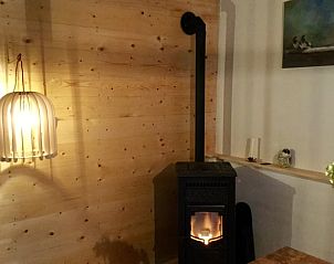 Knusse hoek met houtkachel in Vakantiehuis in Sint Annaparochie, Friesland, perfect voor winteravonden.