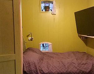 Gezellige slaapkamer in Vakantiehuis in Sint Annaparochie, Friesland, met televisie en rustgevende verlichting.