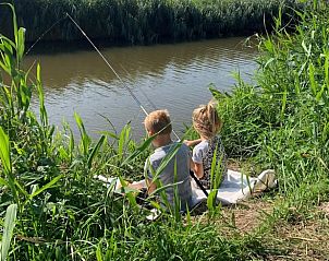 Kinderen vissen aan de waterkant bij Huisje in Sint Annaparochie, gelegen op het Friese platteland, Friesland.