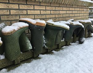 Sneeuw bedekte laarzen bij Huisje in Sint Annaparochie, een winterse sfeer op het Friese platteland, Friesland.