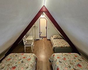 Gezellige zolderkamer in vakantiehuis Jistrum met drie bedden en landelijke uitstraling.