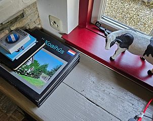 Vensterbank in Huisje in Jistrum met boeken en decoratieve koe.