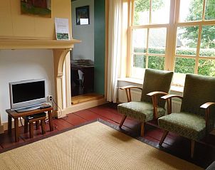 Knusse woonkamer in Vakantiehuis in Jannum met open haard en vintage stoelen, Friesland.