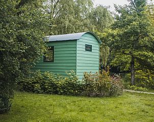 Buitenkant van Vakantiehuis in Waskemeer, Friesland omgeven door weelderige bomen en gras.
