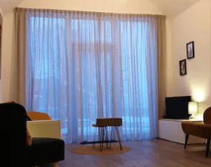 Ruime woonkamer in Vakantiehuisje in Jelsum, Friesland met grote ramen en veel natuurlijk licht.