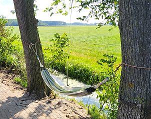 Rustgevende hangmat bij Vakantiehuis in Jelsum, Friesland, met uitzicht op natuur.
