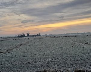 Adembenemend winterlandschap bij vakantiehuisje in Wyns met molen in de verte, Friesland.