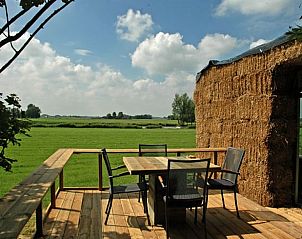 Houten terras bij Vakantiehuis in Wyns met uitzicht op groene velden, Friesland.