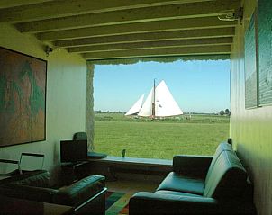 Woonkamer van Vakantiehuis in Wyns met groot raam en uitzicht op zeilboot, Friesland.