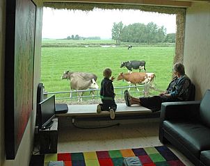 Gezellig interieur van Vakantiehuis in Wyns met uitzicht op grazende koeien, Friesland.