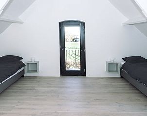 Tweepersoons slaapkamer met balkon in Huisje in Bergharen, vakantieverblijf in Rivierengebied, Gelderland.