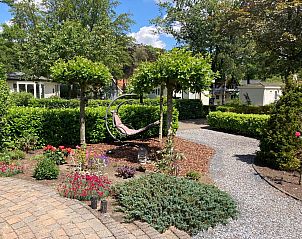 Schaduwrijke tuin met hangstoel bij Chalet in Arnhem, vakantiehuis in Rivierengebied, Gelderland.