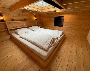 Slaapkamer met houten afwerking in Chalet in Arnhem, biedt comfortabele accommodatie in het Rivierengebied van Gelderland.
