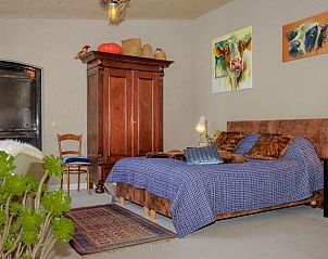 Slaapkamer in Vakantiehuis in Culemborg met kunst en houten meubels.