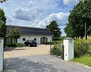 Ingang van Vakantiehuis in Beuningen, Gelderland met ruime parkeerplaats en groene omgeving.
