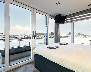 Luxe slaapkamer in The Queen vakantiehuis met panoramisch uitzicht op de jachthaven van Kerkdriel.
