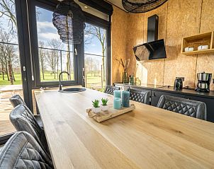 Eettafel in Vakantiehuis Just Nature 4, Kerkdriel, met uitzicht op de groene omgeving.