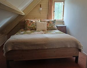 Slaapkamer in Vakantiehuisje in Tricht met comfortabel bed en houten afwerking in Rivierengebied, Gelderland.